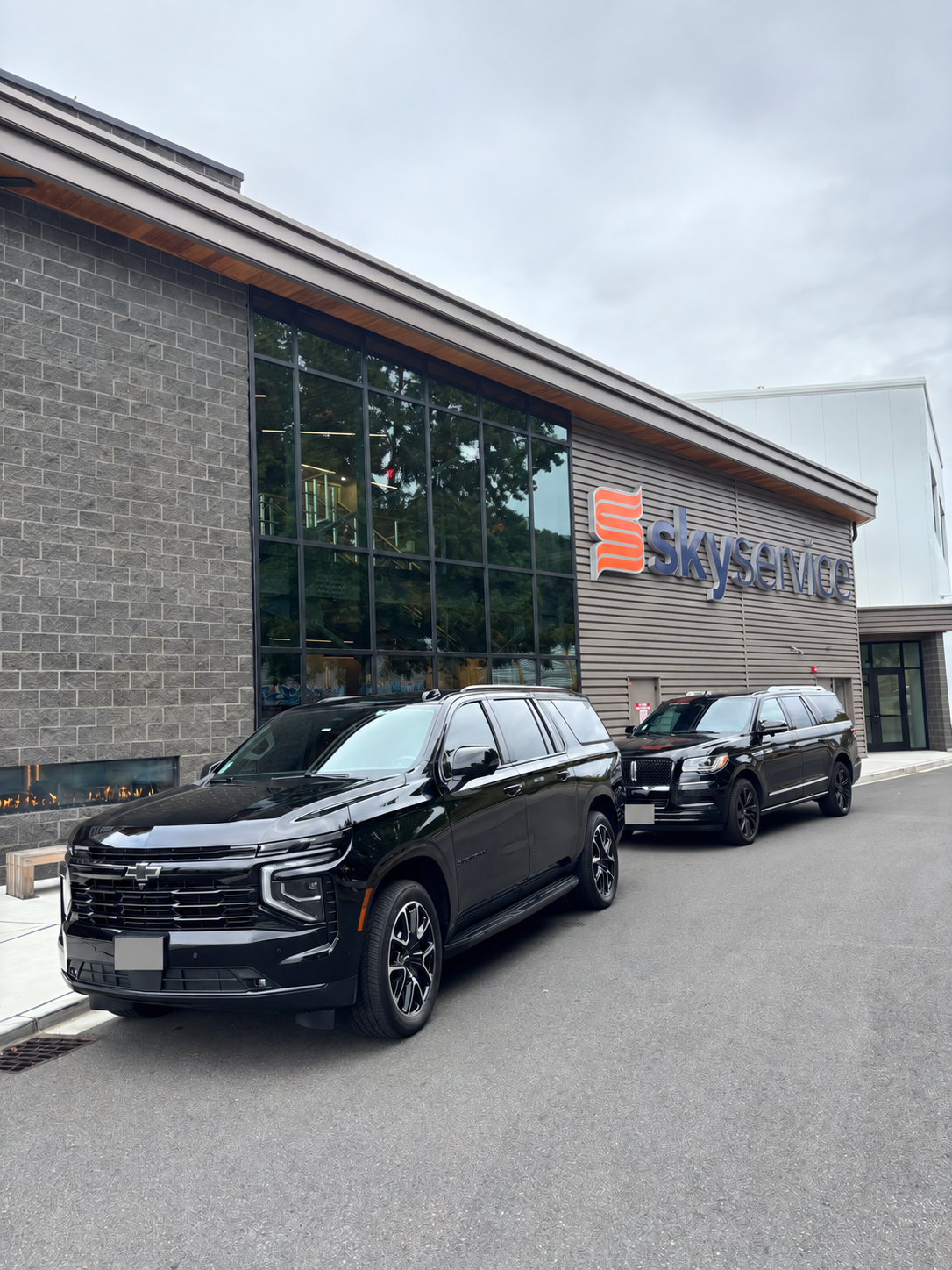 Black Chevrolet Suburban and a second SUV outside the Skyservice building